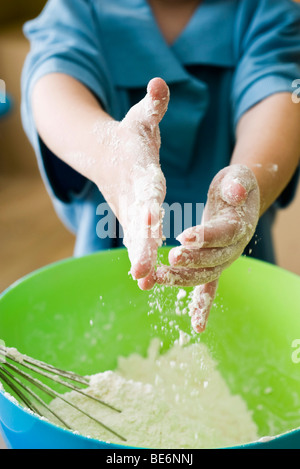 Kleiner Junge Prise Mehl in die Rührschüssel geben Stockfoto