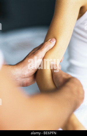 Masseurin massiert Arm des Patienten Stockfoto