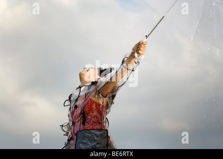 Junge Frau am regnerischen Tag im Freien stehen, so dass Regen fallen auf ihr Gesicht Stockfoto