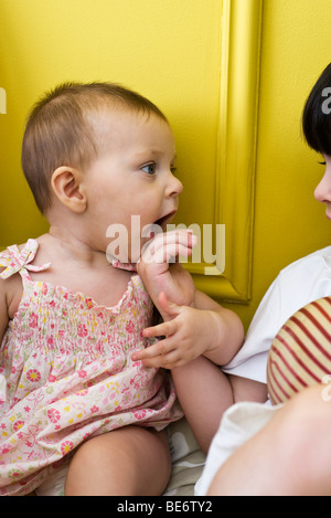 Baby Mädchen festhalten an Bruders Hand, beschnitten Stockfoto