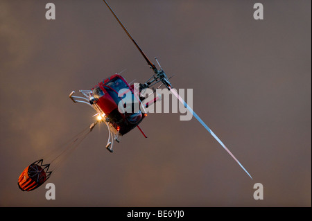 Wasser fallen Hubschrauber kommen, um den Korb mit Wasser aus einem Teich auf einem Golfplatz in der Nähe von Feuer Linien zu füllen. Stockfoto