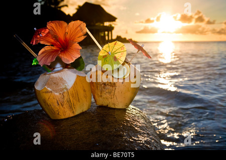 Zwei Kokosnüsse mit Cocktails und Dekorationen auf einem Granitfelsen bei Sonnenuntergang, Seychellen, Indischer Ozean, Afrika Stockfoto