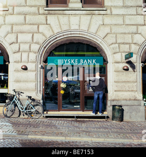 Ein Mann, der Zugriff auf sein Bankkonto Mittel an ein Jyske Bank Geldautomaten mit Fahrrad in Kopenhagen Straße Dänemark Europa KATHY DEWITT Stockfoto