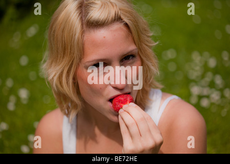 Junges Mädchen essen eine Erdbeere Stockfoto