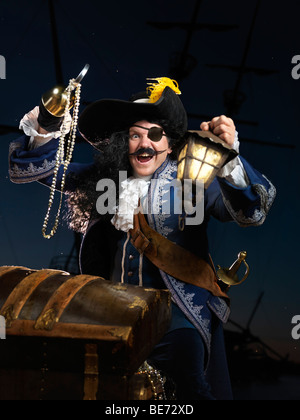 Lizenz erhältlich unter MaximImages.com - Pirat mit Laterne, die eine Schatztruhe öffnet Stockfoto