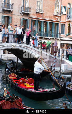 Eine Bootsfahrt durch die wunderschönen Grachten der Stadt übernehmen Gondolieri Touristen nach Venedig. Italien Stockfoto