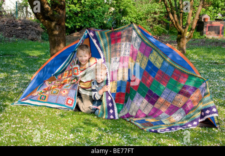 Zwei Jungs, 7 und 5, bauen ein Zelt im Garten