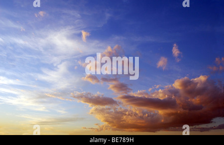 blauer Himmel bei Sonnenuntergang, mit weißen und orangefarbenen Wolken Stockfoto