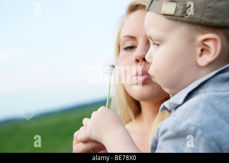 Junge Mutter mit ihrem Sohn, weht eine Löwenzahn Uhr Stockfoto