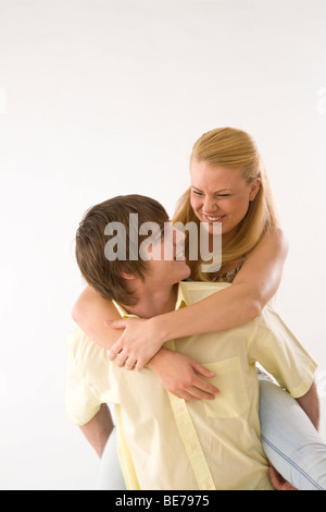 Junger Mann junge Frau Huckepack tragen, lachen Stockfoto