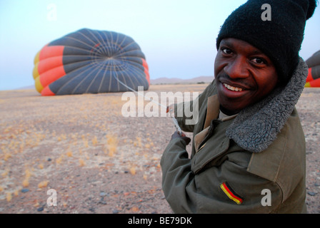 Native tragen ein Bundeswehr Jacke hilft, starten Sie eine Ballonsafari im Morgengrauen, Sossusvlei, Namibia, Afrika Stockfoto