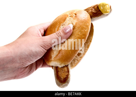 Hand hält eine Bratwurst Wurst im Brötchen mit Senf Stockfoto