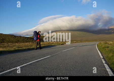 Männliche Anhalter auf leere Bergstraße, Isle Of Skye, Schottland Stockfoto