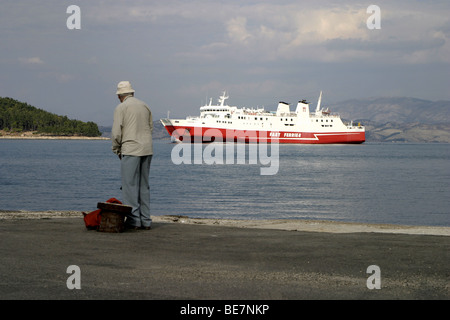 Ein älterer Mann beobachtet, wie die Schnellfähre der griechischen Stadt Igoumenitsa in Korfu ankommt. Stockfoto