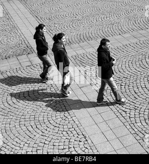 Monochrom von drei Menschen, die zu Fuß über gepflasterten Platz von der Galata Brücke Istanbul Türkei März 2009 Stockfoto