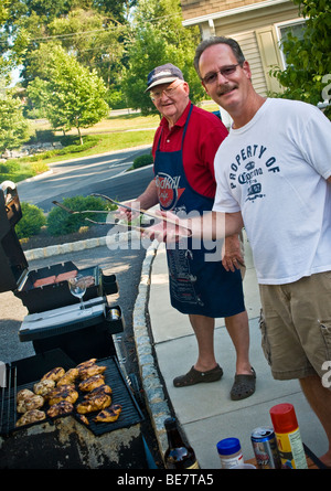 Zwei Köche Hinterhof grill saftige Hamburger Huhn Hotdogs für Nachbarschaft Picknick Stockfoto