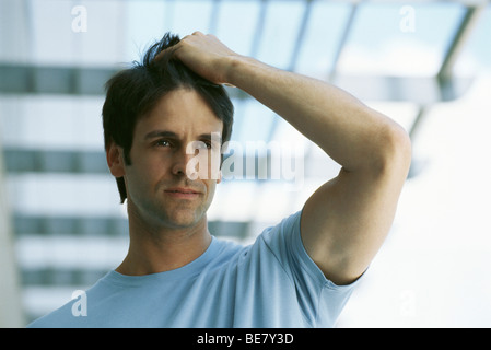 Mann mit Hand auf Kopf nachdenklich wegsehen, Porträt Stockfoto