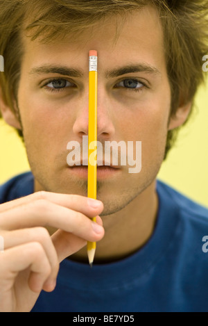 Junger Mann hält Bleistift Stockfoto