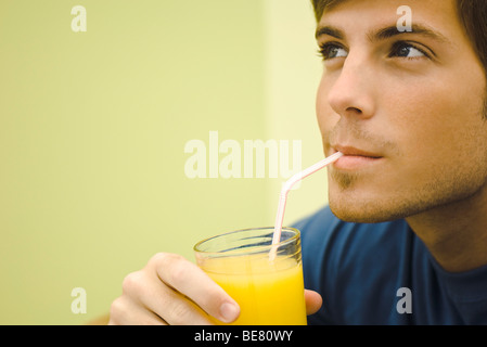Junger Mann Orangensaft trinken Stockfoto