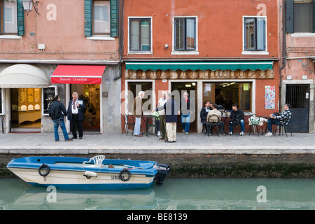 Männer im Gespräch vor einer Bar, Straßenszene am Rio dei Vetrai Kanal, Murano, Veneto, Italien Stockfoto