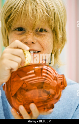 Junge Platzierung Münze im Sparschwein Stockfoto