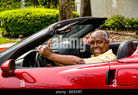 Erfolgreicher ehemaliger senior schwarz afroamerikanischer Mann im Alter von der 70er Jahre in seinem teuren Sportwagen entspannen und glücklich mit ihm Stockfoto