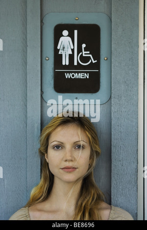 Frau unter Frauen Toilette Schild, Blick in die Kamera Stockfoto