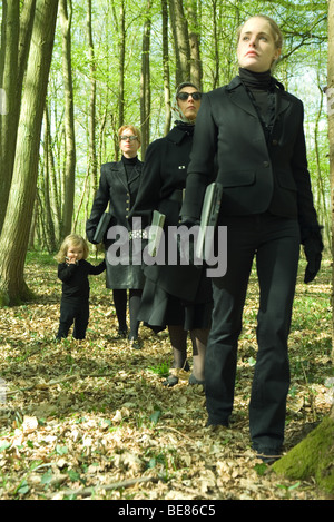 Drei Frauen, die Wandern in Wäldern, die Laptops, kleines Mädchen nach, tragen Handy Stockfoto