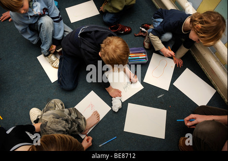 KINDER ZEICHNEN DIE UMRISSE IHRER FÜßE IN EINER GRUPPE AN EINEM SONNTAG SCHOOL UK Stockfoto