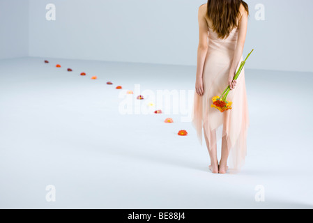 Frau mit Blumenstrauß Rücken Weg der Blumen führt weg von ihr, Rückansicht Stockfoto