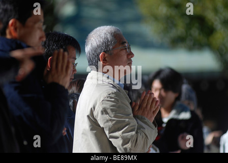 JAPAN Honshu Tokio Jingumae - an Meijijingu Schrein der New Years Gläubige beten mit den Händen umklammert zusammen Stockfoto