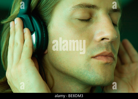 Mann mit Augen geschlossen anhören von Musik über Kopfhörer, Nahaufnahme Stockfoto