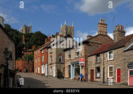 Alte Häuser auf einer Bergstraße, steile Hügel, vor den Türmen der Kathedrale von Lincoln, Lincoln, Lincolnshire, England, USA Stockfoto