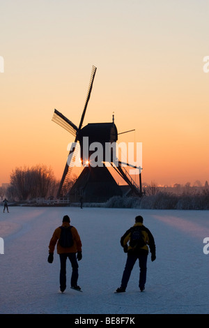 Schaatsers Schaatsen Langs de Molens van Kinderdijk; Eisläufer Skate entlang der Windmühlen von Kinderdijk Stockfoto