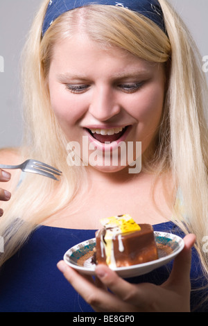 Dicke junge Frau isst Kuchen. Stockfoto