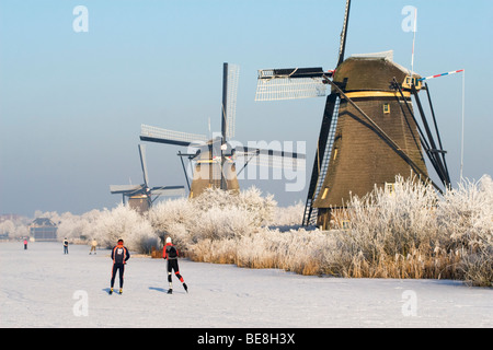 Schaatsers Schaatsen Langs de Molens van Kinderdijk; Eisläufer Skate entlang der Windmühlen von Kinderdijk Stockfoto