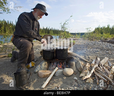 Mann, Kochen am Lagerfeuer, Töpfe, Wasserkocher, oben Liard River, Yukon Territorium, Kanada Stockfoto