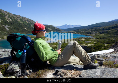 Junge Frau ruht, Wanderer mit Rucksack, Trinkflasche, Panorama, tiefer See hinter historischen Chilkoot Trail, Chilkoot Pass, alp Stockfoto
