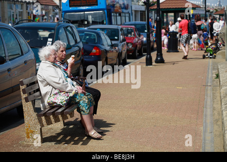 zwei ältere Leute sitzen auf einer Bank am Strand ein Eis essen Stockfoto