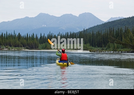 Frau im Kajak, Paddeln, Kajak fahren, oben Liard River, Pelly Bergen im Hintergrund, Yukonterritorium, Kanada Stockfoto
