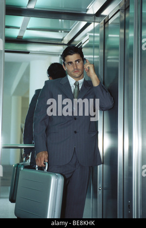 Kaufmann im Aufzug mit Handy Stockfoto