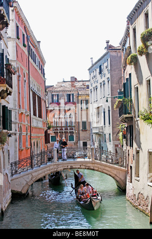 Eine Bootsfahrt durch die wunderschönen Grachten der Stadt übernehmen Gondolieri Touristen nach Venedig. Italien Stockfoto