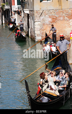 Eine Bootsfahrt durch die wunderschönen Grachten der Stadt übernehmen Gondolieri Touristen nach Venedig. Italien Stockfoto