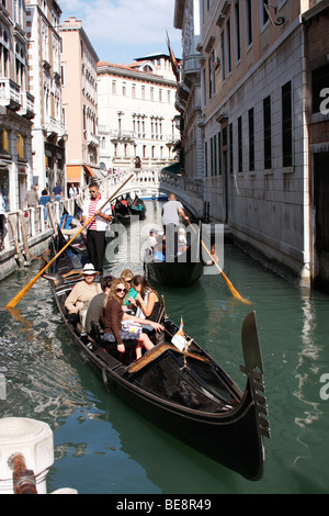 Eine Bootsfahrt durch die wunderschönen Grachten der Stadt übernehmen Gondolieri Touristen nach Venedig. Italien Stockfoto