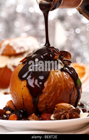 Bratapfel mit Nüssen, Rosinen und Marzipan, mit Schokosauce gegossen auf festliche Atmosphäre Stockfoto