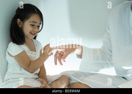 Kleines Mädchen mit Finger des Vaters, beschnitten Stockfoto