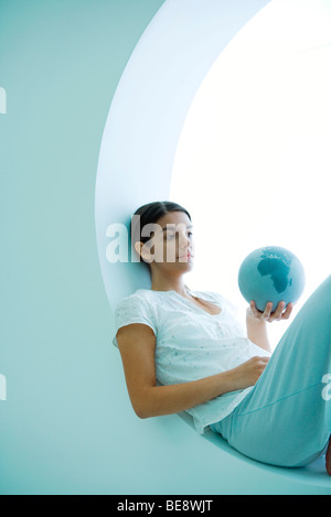 Junge Frau liegend, Blick in die Welt in der hand Stockfoto