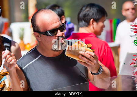 Mann isst Wurst Fest des San Gennaro Festival in Little Italy in New York City Stockfoto