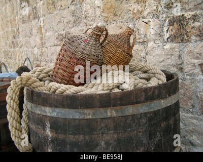 Kroatien; Hrvartska; Fernsehreihe; Dubrovnik Altstadt, zwei Wicker bedeckt in Flaschen, am Seil, auf Holzfass Stockfoto