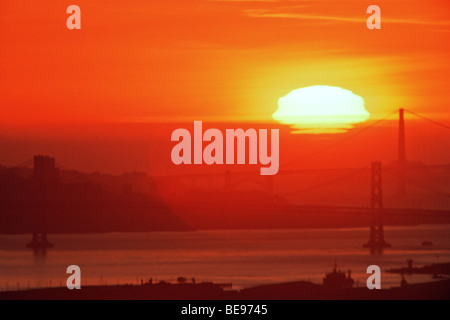 Sonnenuntergang hinter Bay Bridge & Golden Gate Bridge in San Francisco Bay, CA, USA Stockfoto